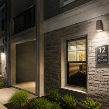 Modern building exterior with a window, door, and address sign at night.